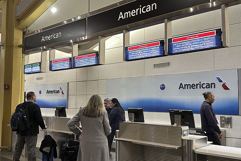 Signs display an 'Emergency Alert' above an American Airlines counter in the terminal at Ronald Reagan Washington National Airport, 29 January, 2025