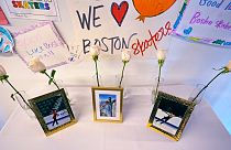 Six white roses and photographs of victims are displayed at The Skating Club of Boston, Thursday, Jan. 30, 2025, in Norwood, Mass.