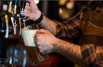 Close up photo of a bartender pouring beer into a beer glass at a pub.