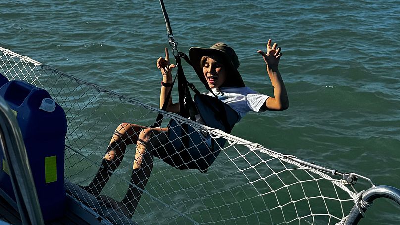 Skye has fun dangling from the sailboat over the ocean