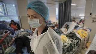 A member of the medical staff walks in a crowded COVID-19 isolation room at the University Emergency Hospital in Bucharest, 22 October, 2021