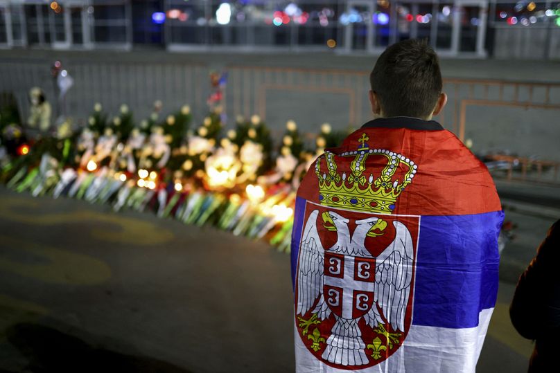 Ένα αγόρι τυλιγμένο με τη σερβική σημαία στέκεται στο σημείο της κατάρρευσης του τσιμεντένιου στεγάστρου στο Νόβι Σαντ, 31 Ιανουαρίου 2025