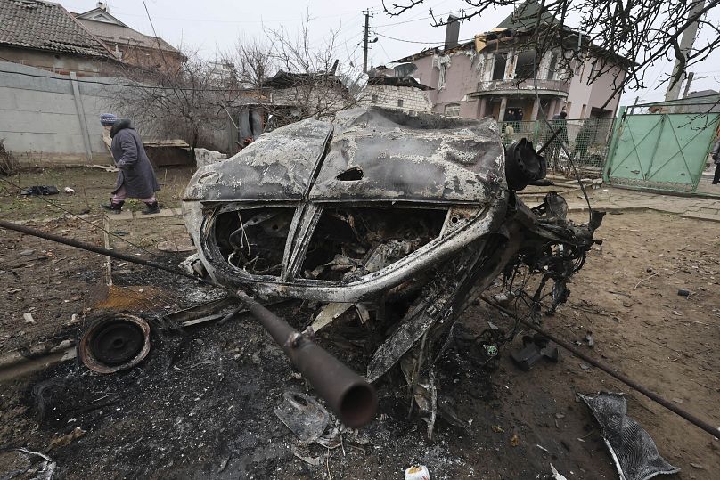 Une femme marche devant une voiture détruite par une frappe russe sur un quartier résidentiel de Zaporijjia, en Ukraine, le 1er février 2025.