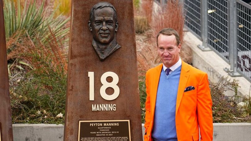 Minden idők egyik legjobbnak tartott NFL-játékosa, a már visszavonult kétszeres Super Bowl-győztes Peyton Manning az őt ábrázoló oszlop előtt Denverben 2021. október 31-én.