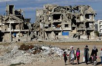FILE: Syrian citizens walk in front of buildings that were destroyed in Manbij, north Syria, March 31, 2018.