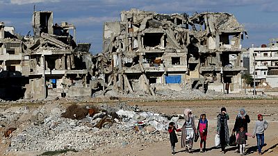 DATEI: Syrische Bürger gehen vor zerstörten Gebäuden in Manbij, Nordsyrien, 31. März 2018.