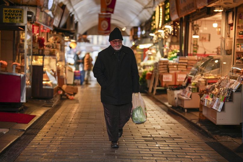 رجل يحمل كيسا يحتوي على مواد غذائية في سوق طعام في حي أوسكودار في إسطنبول بتركيا 23 كانون الثاني يناير 2025