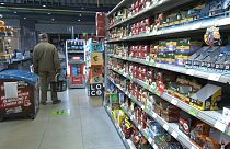 A man is standing in the isle as he is shopping in a grocery store in Serbia. 