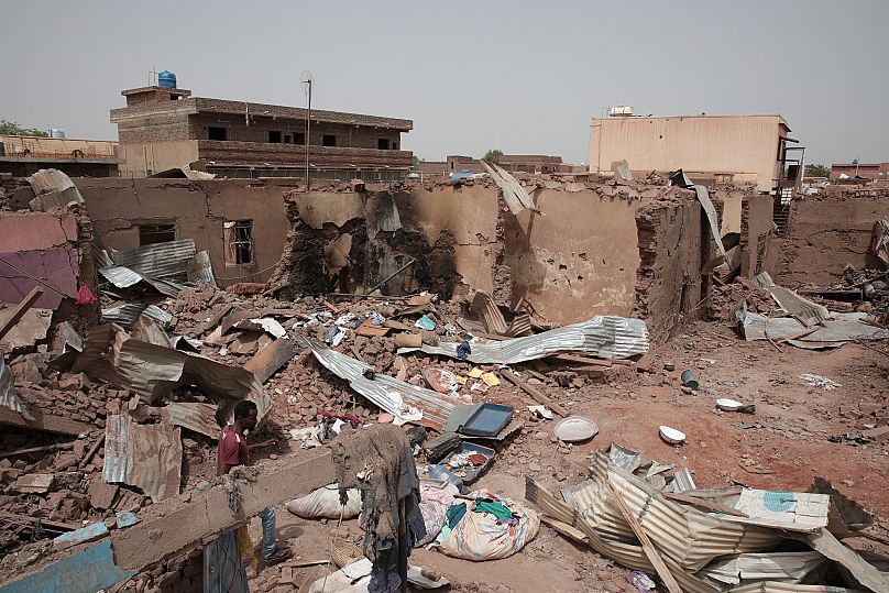 رجل يمشي بجوار منزل أصيب في القتال الأخير في الخرطوم، السودان، وهي منطقة مزقها القتال بين الجيش وقوات الدعم السريع شبه العسكرية سيئة السمعة، 25 أبريل/نيسان 2023