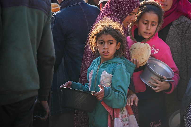 فتيات فلسطينيات يجمعن المواد الغذائية المتبرع بها في مركز لتوزيع المواد الغذائية في دير البلح وسط قطاع غزة، الخميس 2 يناير/كانون الثاني 2025