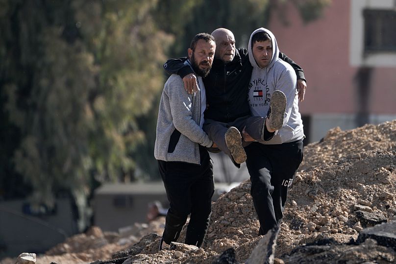 فلسطينيون نازحون بسبب عملية عسكرية إسرائيلية يحملون رجلًا مسنًا فوق الأنقاض أثناء إجلائهم من مخيم جنين للاجئين في الضفة الغربية يوم الخميس، 23 يناير 2025