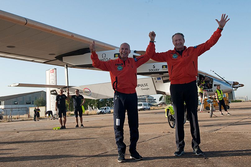 Pilotlar Bertrand Piccard (solda) ve Andre Borschberg (sağda), İspanya'nın Sevilla kentindeki San Pablo havaalanında güneş enerjisiyle çalışan uçağın inişini kutluyor. Perşembe, 23 Haziran 2016.