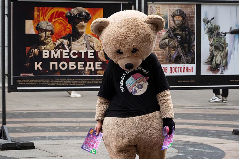 Ein Straßenkünstler vor einer Plakatreihe über die russische Armee, St. Petersburg, 28. Dezember 2024