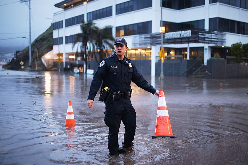 Egy rendőr áll egy elárasztott kereszteződésben 2025. február 13-án, a Los Angeles-i Pacific Palisades negyedben.