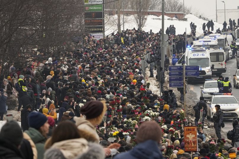 Polis (sağda), Rusya'nın başkenti Moskova'da muhalefet lideri Aleksey Navalny'nin cenaze töreni için Borisovskoye Mezarlığı'na doğru yürüyen insanları izliyor, 1 Mart 2024.