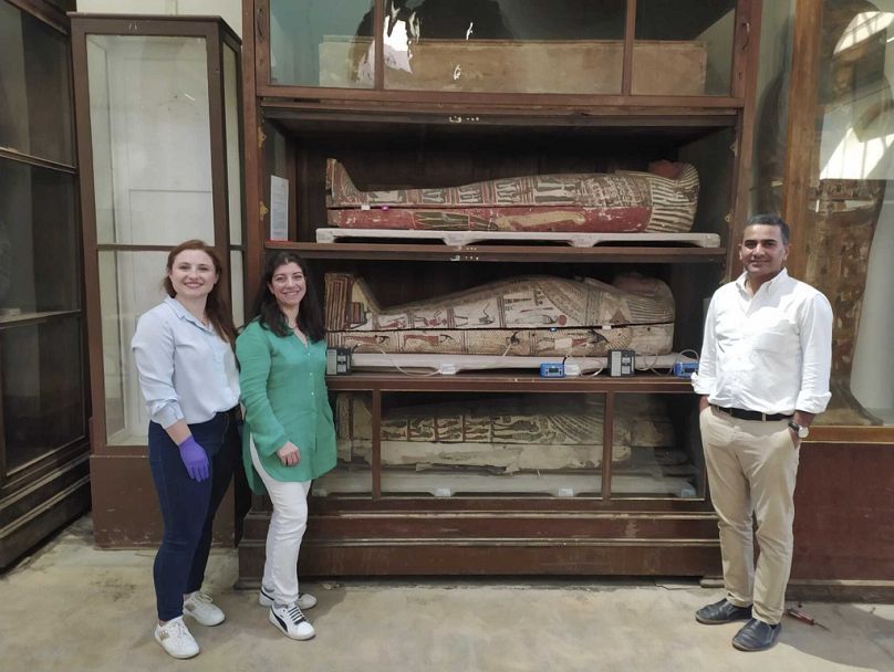 Parte da equipa de investigação do Museu Egípcio no Cairo posa para uma fotografia junto de uma seleção de corpos mumificados.