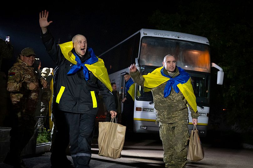 Des militaires ukrainiens crient « Gloire à l'Ukraine » avec des drapeaux nationaux après leur retour de captivité lors d'un échange de prisonniers de guerre.