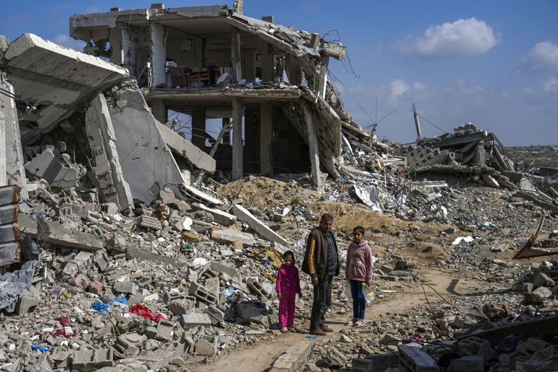 فلسطينيون يقفون وسط أنقاض المنازل بفعل الحرب الإسرائيلية، في مخيم البريج للاجئين وسط قطاع غزة، يوم الإثنين 17 فبراير 2025.