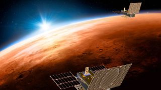 This illustration made available by NASA on March 29, 2018 shows the twin Mars Cube One (MarCO) spacecraft flying over Mars with Earth and the sun in the distance