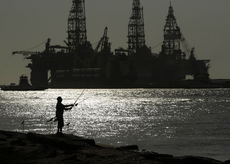  A man wears a face mark as he fishes near docked oil drilling platforms off the coast of Texas. 