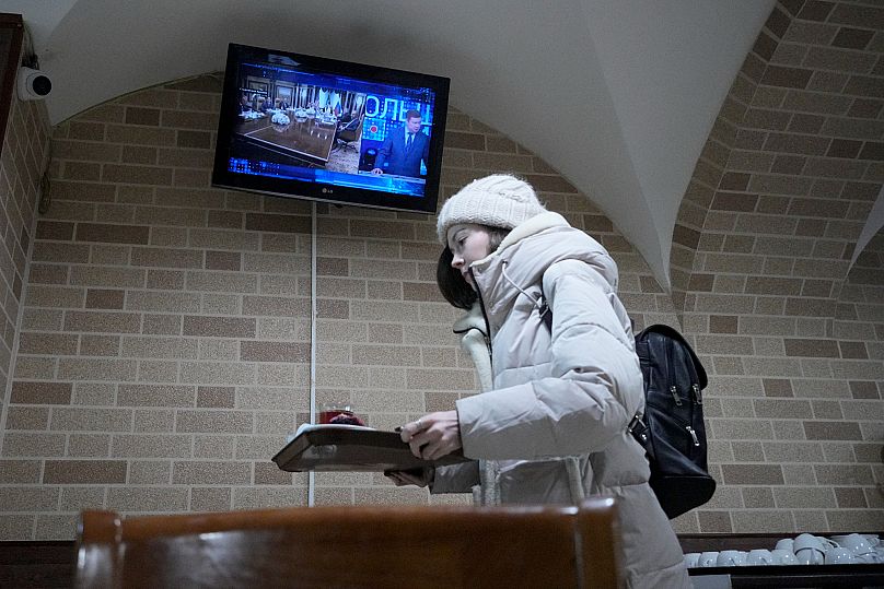 Une femme passe devant un écran de télévision à Saint-Pétersbourg diffusant des informations sur les pourparlers entre les États-Unis et la Russie en Arabie saoudite, 18.02.25