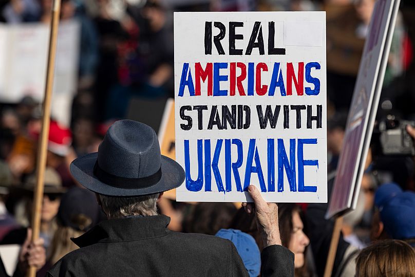 Bir gösterici, ABD Başkanı Donald Trump'ın politikalarını protesto etmek için Los Angeles'ta düzenlenen bir miting sırasında bir poster tutuyor, 17 Şubat 2025.