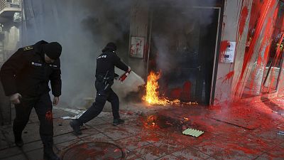 Police a fire set by nationalist protesters at the EU commission office door in Sofia, 22 February, 2025