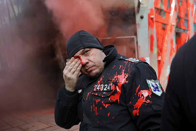 A policeman holds his eye during clashes with nationalist protesters who demanded the government scrap plans to take the country into the eurozone, 22 February, 2025