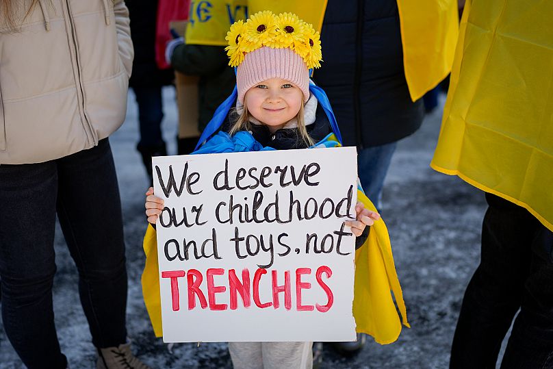 Une enfants brandit une affiche sur laquelle il est écrit 'Nous méritons notre enfance et de jouets, pas des tranchées", le 23 février 2025