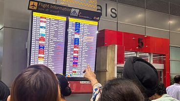 People at the New Delhi international airport read an electronic display showing an American Airlines flight from New York was diverted to Rome, 23 February 2025