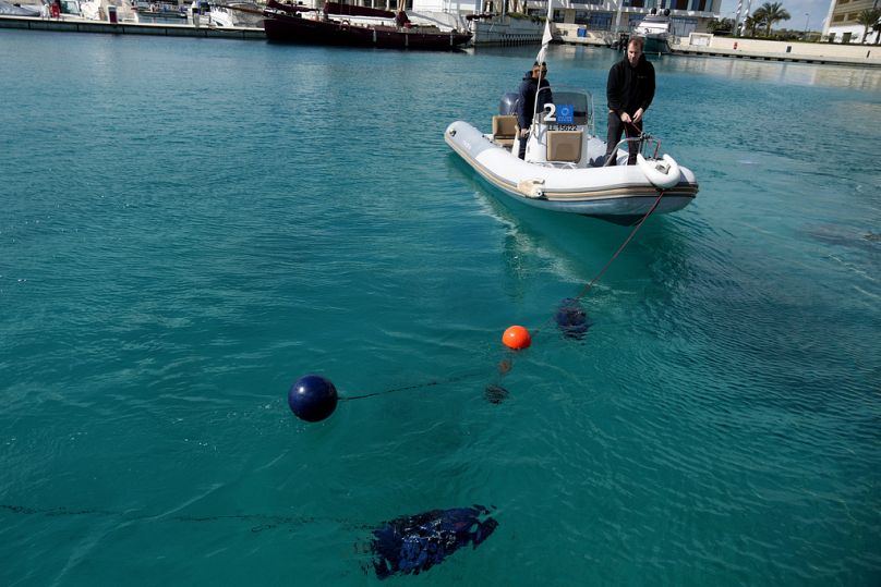 An assistance boat with two personnel monitors an underwater drone at a Marina in southern resort of Ayia Napa, Cyprus.