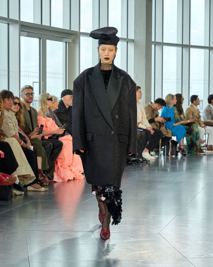 A model hits the runway in a sleek black ensemble on the ROKSANDA runway at London Fashion Week.