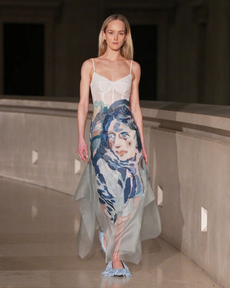 A model walks down the ERDEM runway wearing a dress created in collaboration with Scottish figurative painter Kaye Donachie at London Fashion Week. 