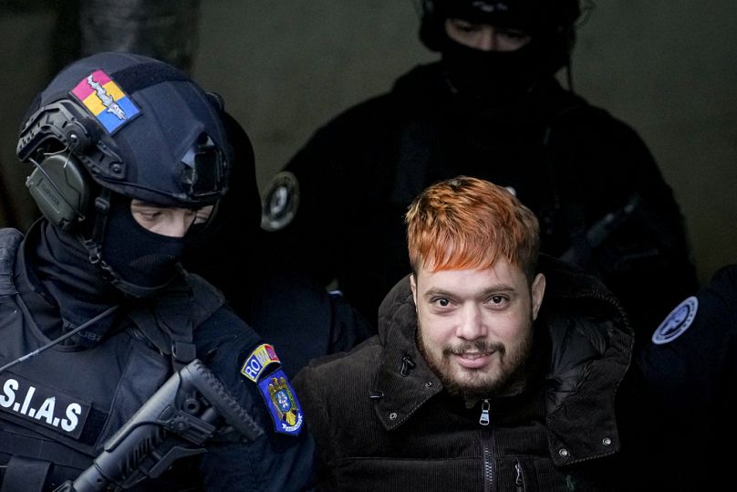 Des policiers escortent Mohamed Amra, après une audience à la cour d'appel de Bucarest, en Roumanie, dimanche 23 février.