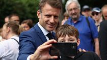 French President Emmanuel Macron takes a selfie with a boy after voting in Le Touquet-Paris-Plage, northern France, Sunday, June 30, 2024. 