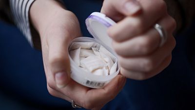 A woman opens a box of nicotine pouches in Stockholm in April 2022.