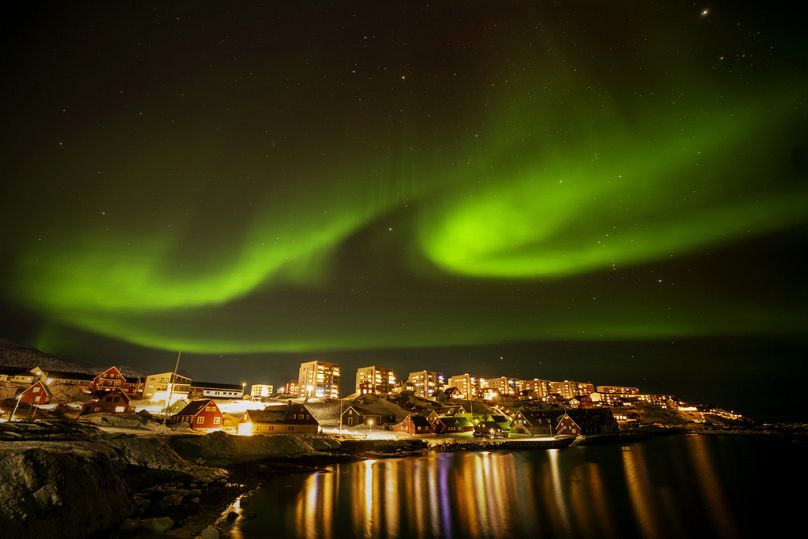 Zorza polarna pojawia się nad domami w Nuuk, Grenlandia.