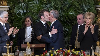 Portuguese President Marcelo Rebelo de Sousa and French President Emmanuel Macron embrace following their speeches during a state dinner at the Ajuda National Palace in Lisbon