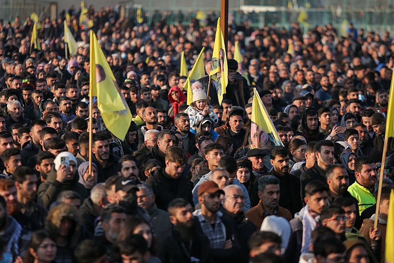 حشد من الناس يشاهدون أعضاء الوفد المؤيد لزعيم حزب العمال الكردستاني المسجون في القامشلي، شمال شرق سوريا، 27 فبراير/شباط 2025.