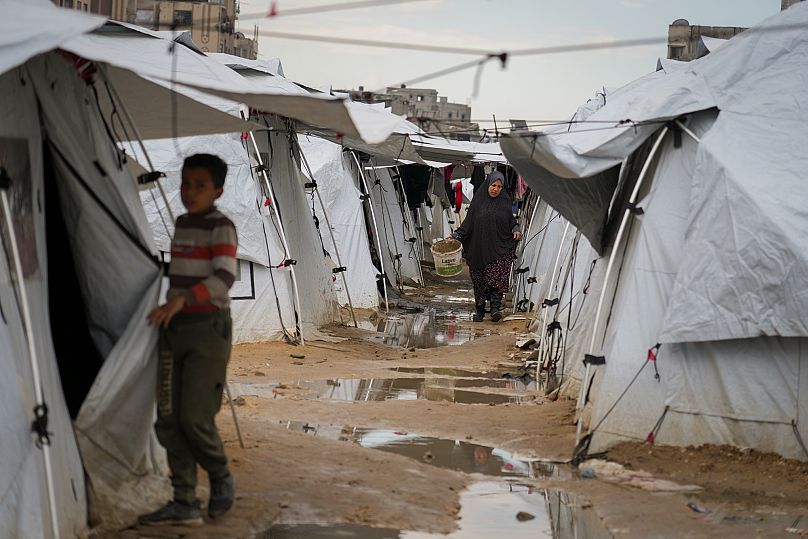 امرأة فلسطينية  تسير بين الخيام في مخيم  مجاور للمنازل المدمرة في مدينة غزة، قطاع غزة، السبت 1 مارس/آذار 2025