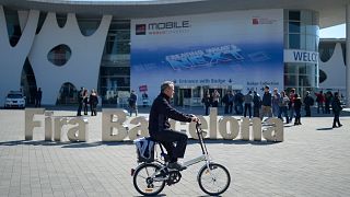 A man rides his bicycle outside the Mobile World Congress, the world's largest mobile phone trade show in Barcelona, Spain, Sunday, Feb. 23, 2014.