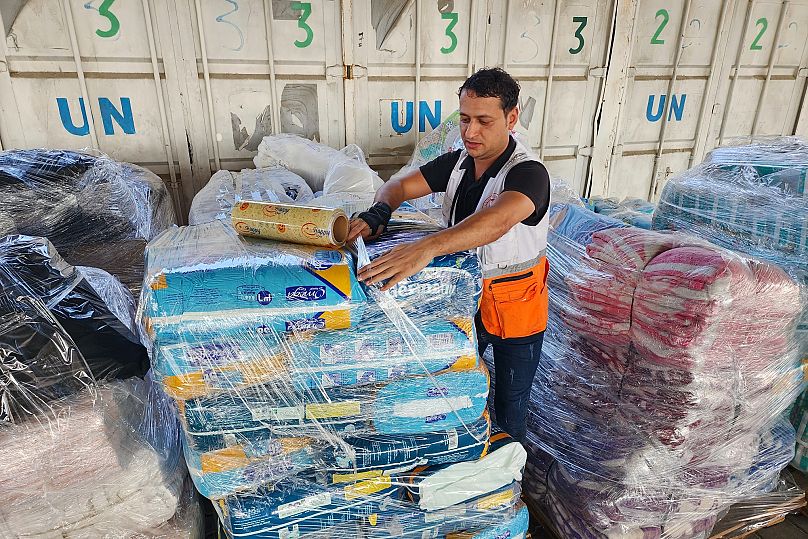 United Nations and Red Crescent workers prepare aid for distribution at an UNRWA warehouse in Deir Al-Balah, 23 October, 2023