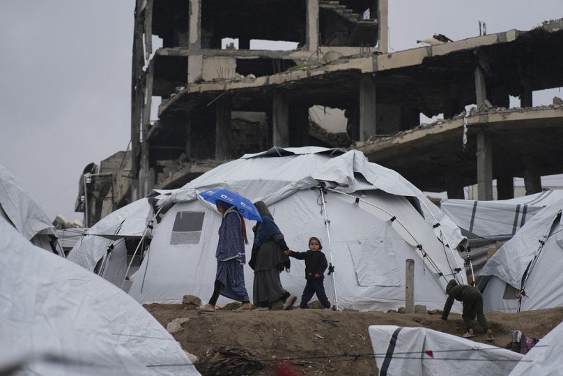 أسرة فلسطينية تسير بين الخيام في مدينة غزة، قطاع غزة، السبت، 1 آذار/مارس 2025.
