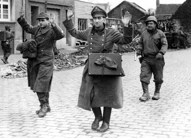 سربازان آمریکایی در حال تصرف شهر کلن دو سرباز آلمانی را اسیر کرده و به اردوگاه اسرای جنگی می‌برند