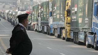 Datoteka: Egipatski policajac stoji ispred kamiona humanitarne pomoći za Gazu na parkiralištu u Kairu, 26. siječnja 2025.