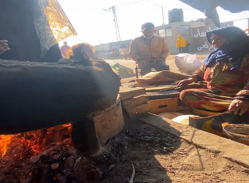 أم منتصر سيدة فلسطينية من غزة أمام فرن طيني