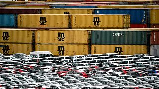 Automobili za izvoz i uvoz čuvaju se ispred kontejnera u četvrtak, 16. svibnja 2019. u luci u Bremerhavenu u Njemačkoj