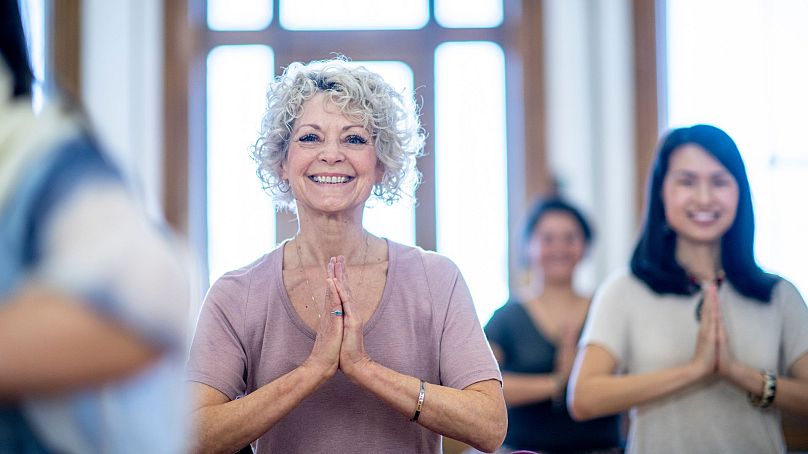 Older woman smiles while doing yoga