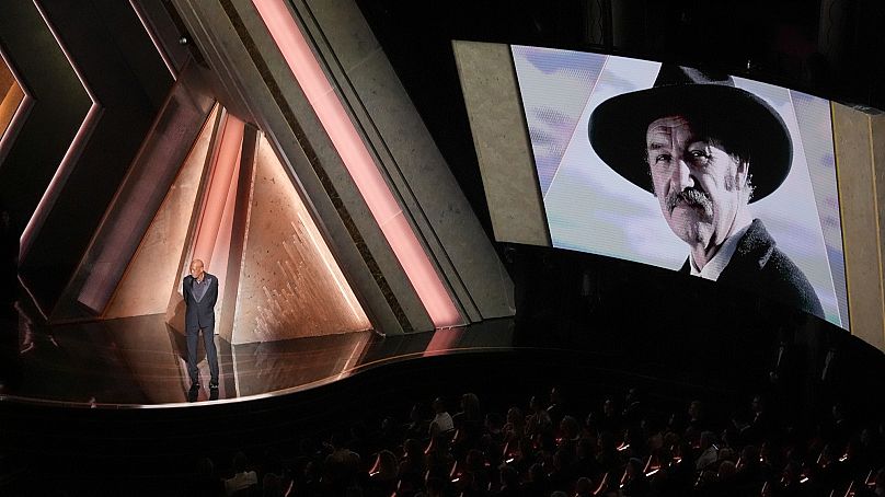 Morgan Freeman speaks about Gene Hackman with an image of Gene Hackman on the screen during the Oscars on Sunday, March 2, 2025, at the Dolby Theatre in Los Angeles.