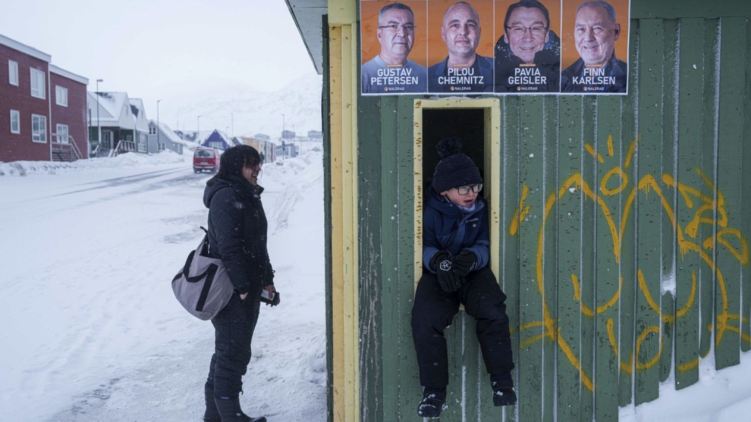 A boy sits at the bus station with political placards for the upcoming elections displayed in Nuuk, Greenland, Saturday, March 8, 2025.